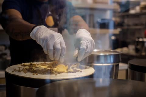 Batter poured from a ladle onto the hot tawa