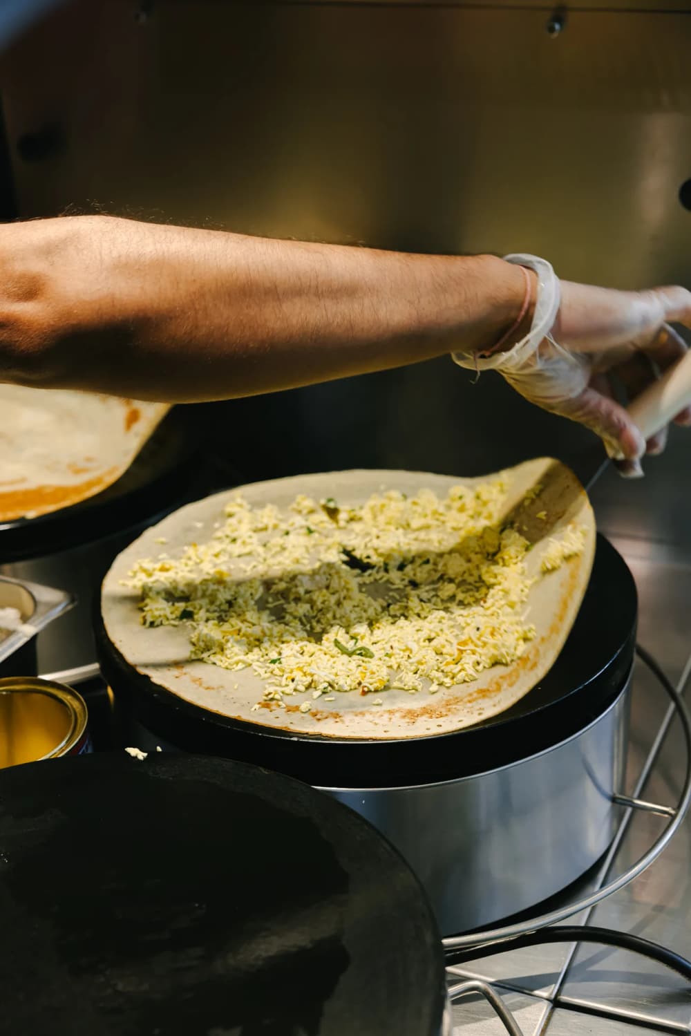A dosa spread with filling on a hot griddle