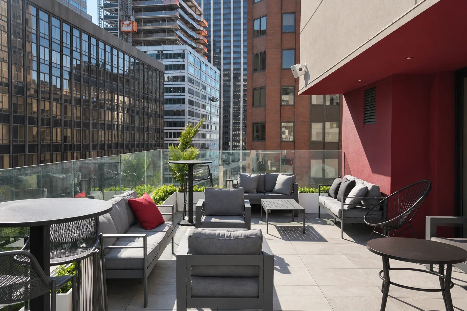 Rooftop terrace seating beside a red wall and glass railing