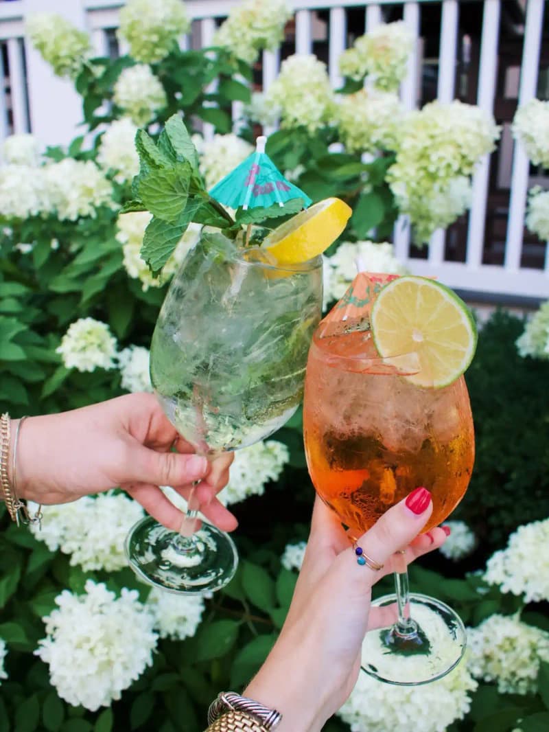Two spritz cocktails raised in a toast outdoors