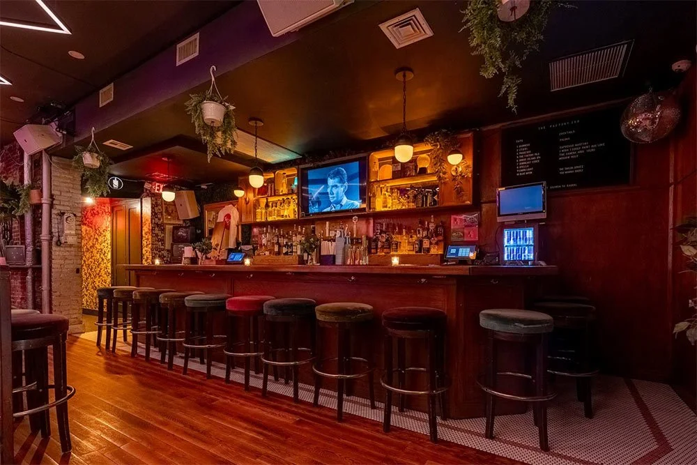 Wood bar with velvet stools, TVs and hanging plants at The Factory 380