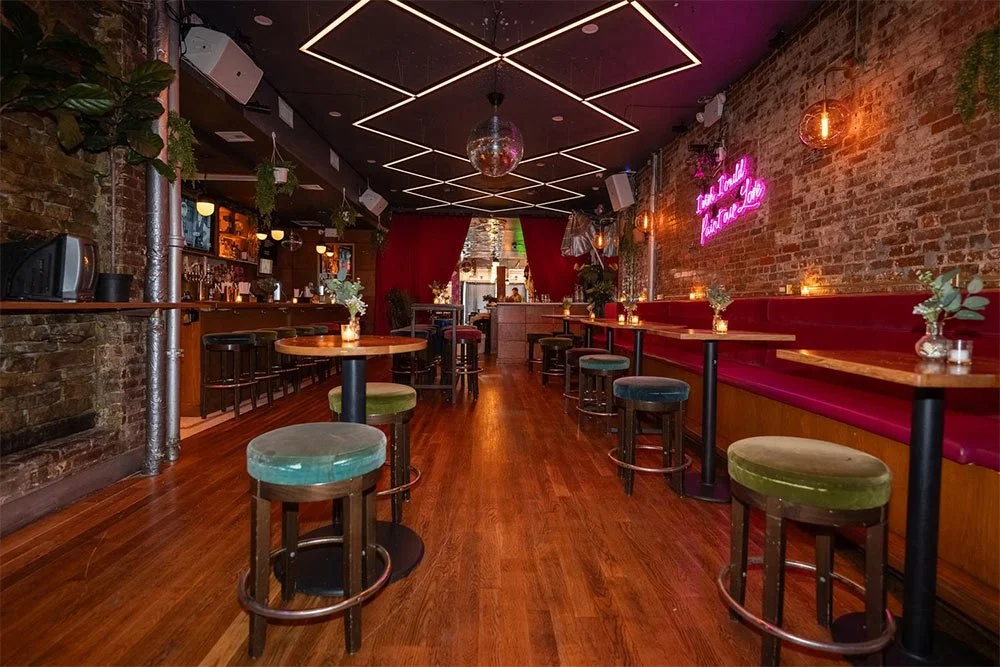 Long room with high-top tables, velvet stools, a pink banquette and a disco ball at The Factory 380